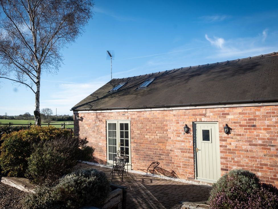 An exterior view of a brick cottage with a door and windows at Barnfields Holiday Cottage in Kingsley