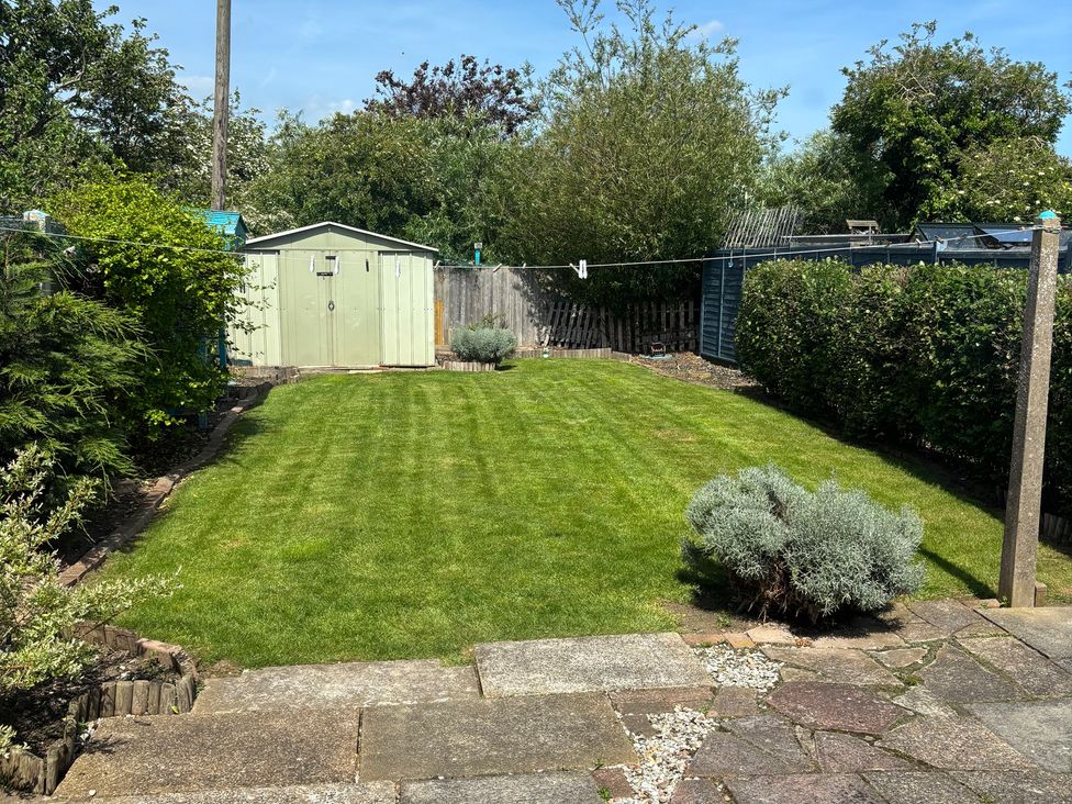 A garden with grass and a shed at Herby's Retreat in Sutton-On-Sea