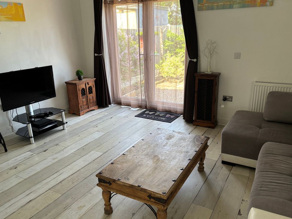 A living room with a television, sofa, and coffee table at Herby's Retreat in Sutton-On-Sea