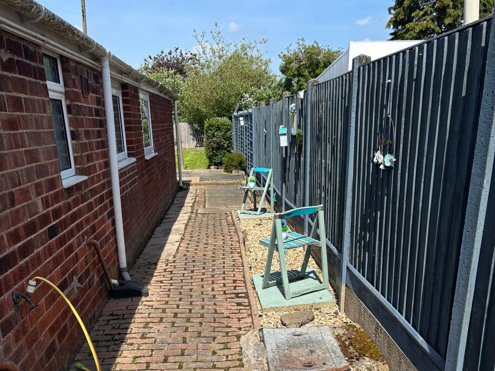 A pathway with chairs and fences at Herby's Retreat Sutton-On-Sea