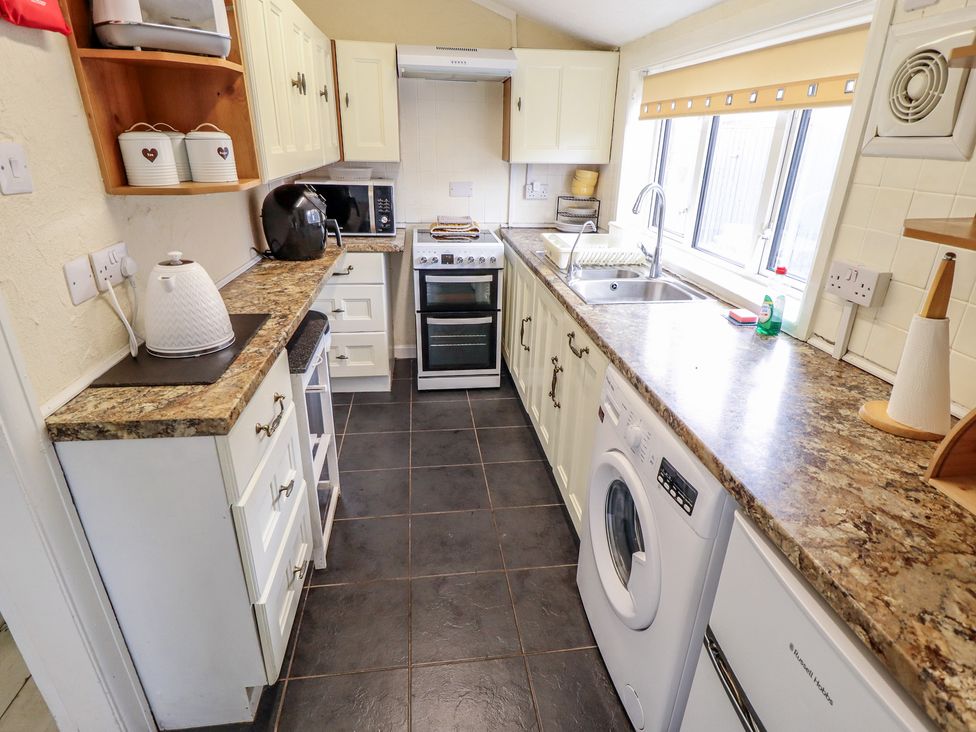 A kitchen with cabinets and appliances at Herby's Retreat in Sutton-On-Sea