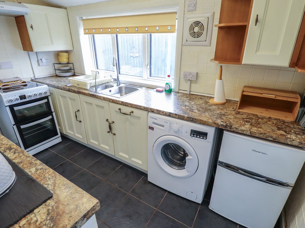 A kitchen with an oven, sink, and washing machine at Herby's Retreat in Sutton-On-Sea