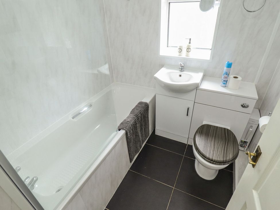 A bathroom with a bathtub, sink, and toilet at Herby's Retreat in Sutton-On-Sea