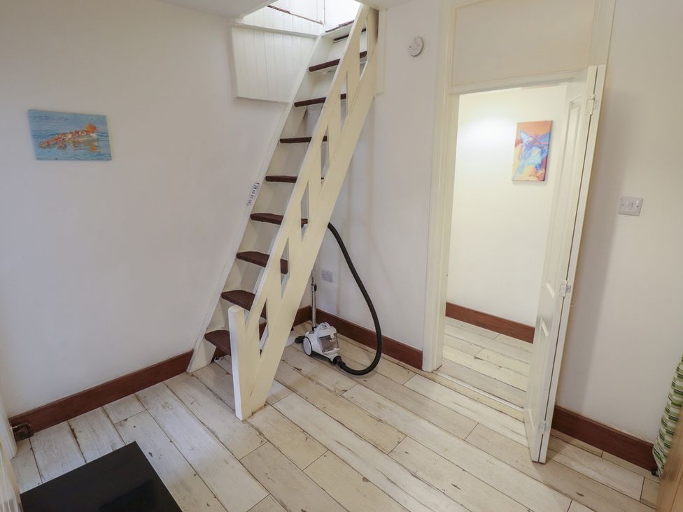 A hallway with a staircase and vacuum cleaner at Herby's Retreat in Sutton-On-Sea