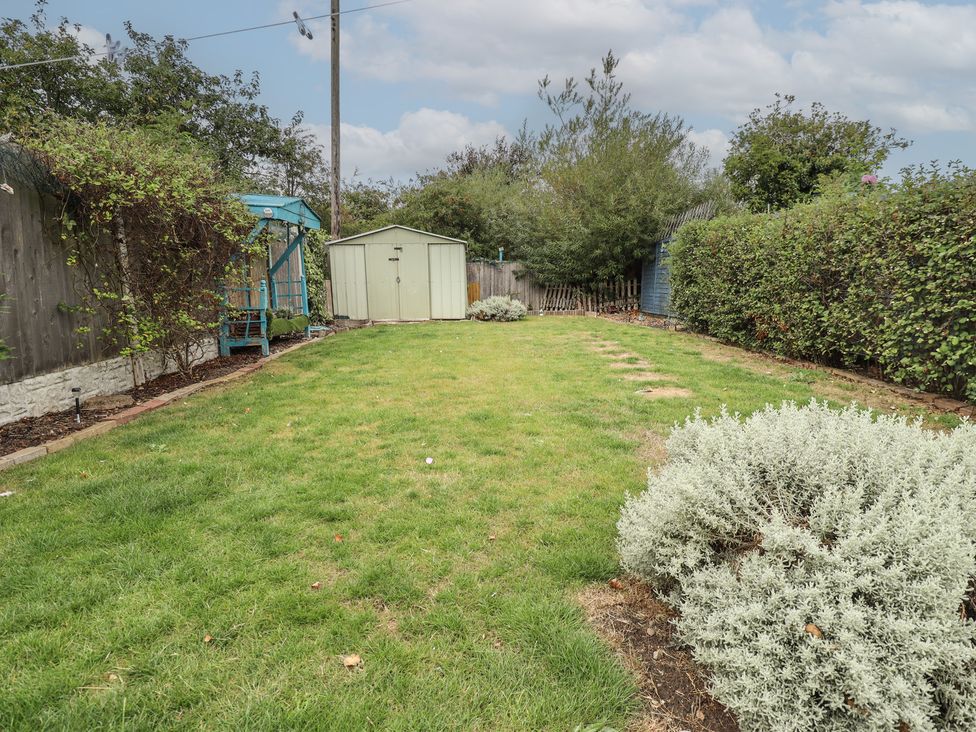 A garden with grass and a shed at Herby's Retreat in Sutton-On-Sea