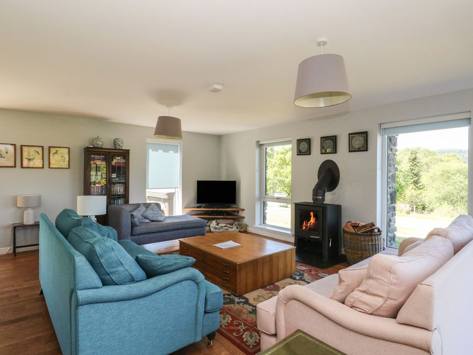 A living room with sofas a wooden coffee table a television and a wood burning stove at Sobrachan in Kilmartin