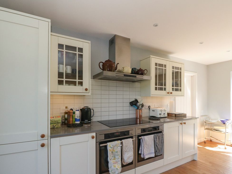 A kitchen with white cabinets a countertop with a kettle toaster teapots and two ovens with towels at Sobrachan in Kilmartin