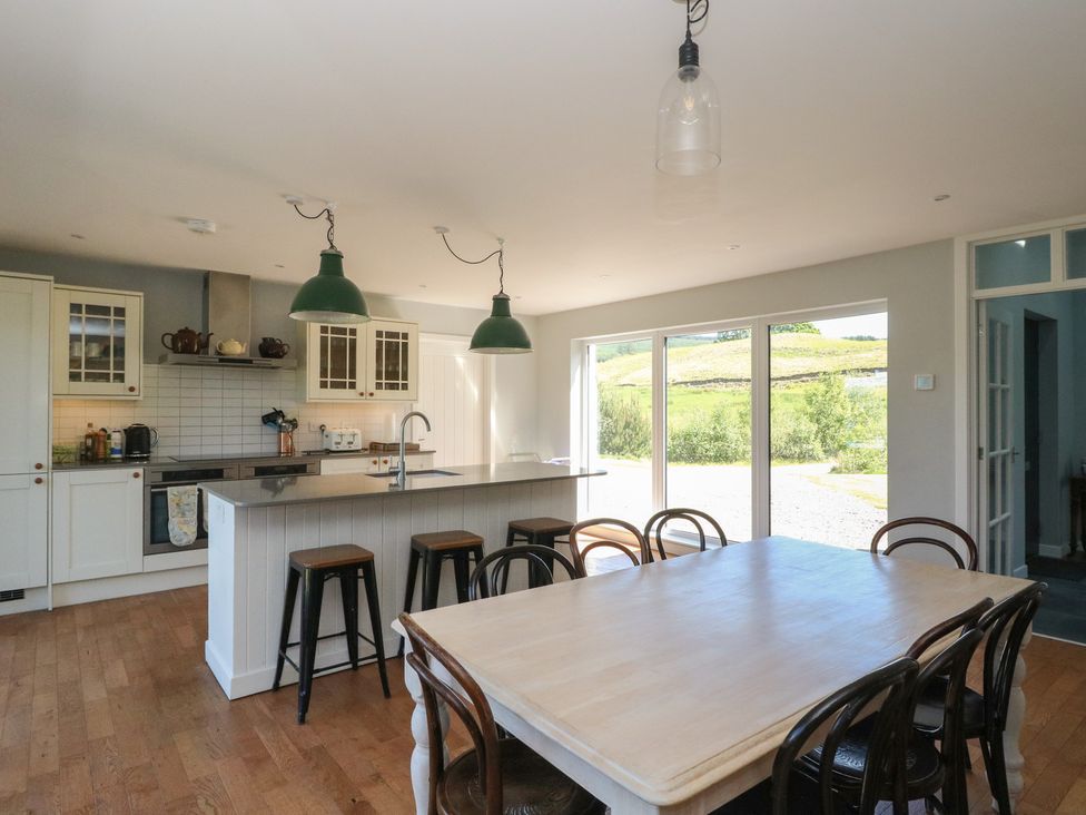 A kitchen with a dining table and chairs next to large glass doors showing an outdoor view at Sobrachan in Kilmartin