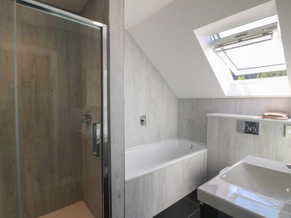 A bathroom with a bathtub a shower stall a sink and a skylight window at Sobrachan in Kilmartin