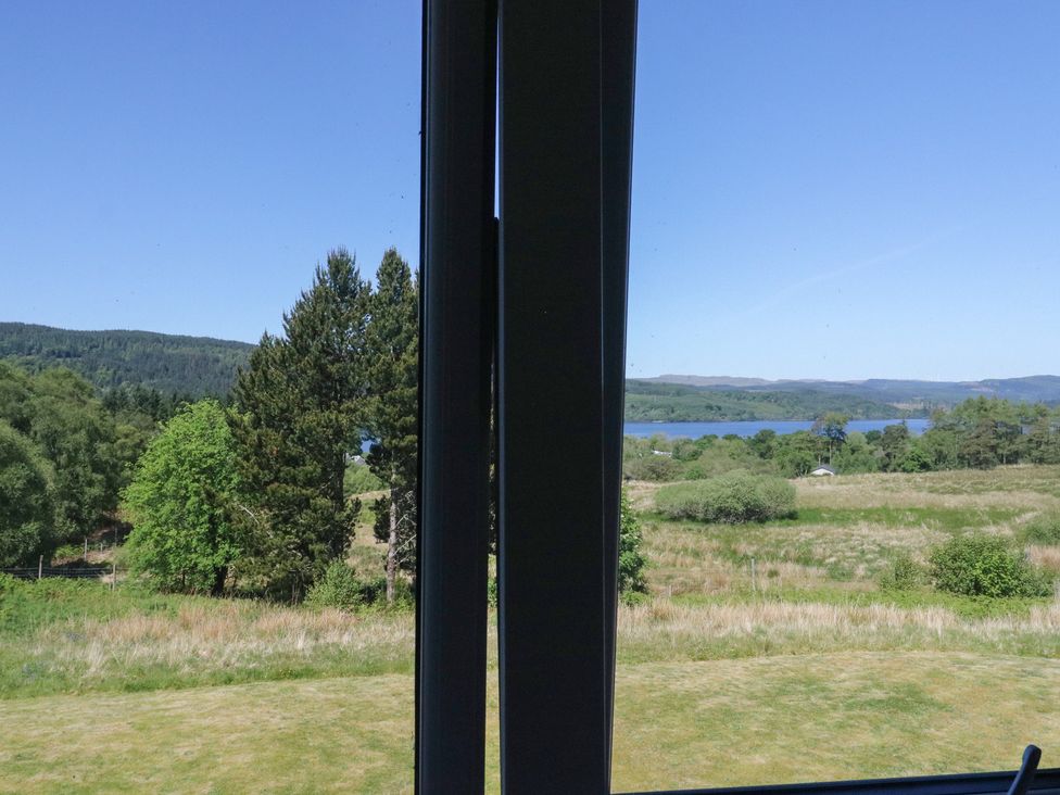 A view of trees and a lake through a window at Sobrachan in Kilmartin