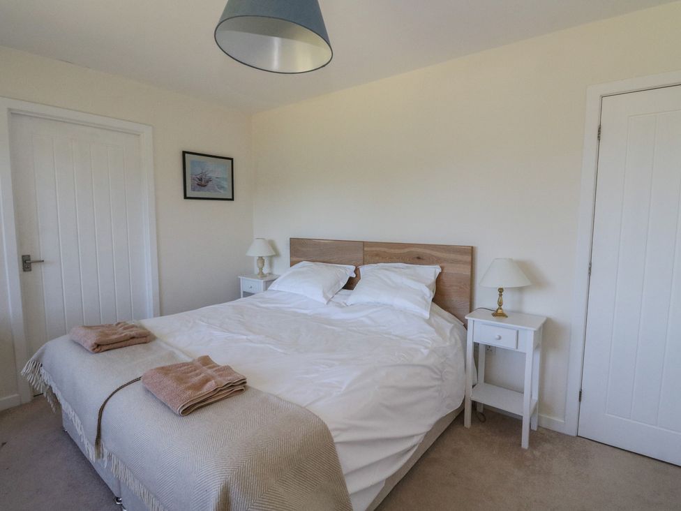 A bedroom with a double bed two bedside tables with lamps two doors and a framed picture on the wall at Sobrachan in Kilmartin