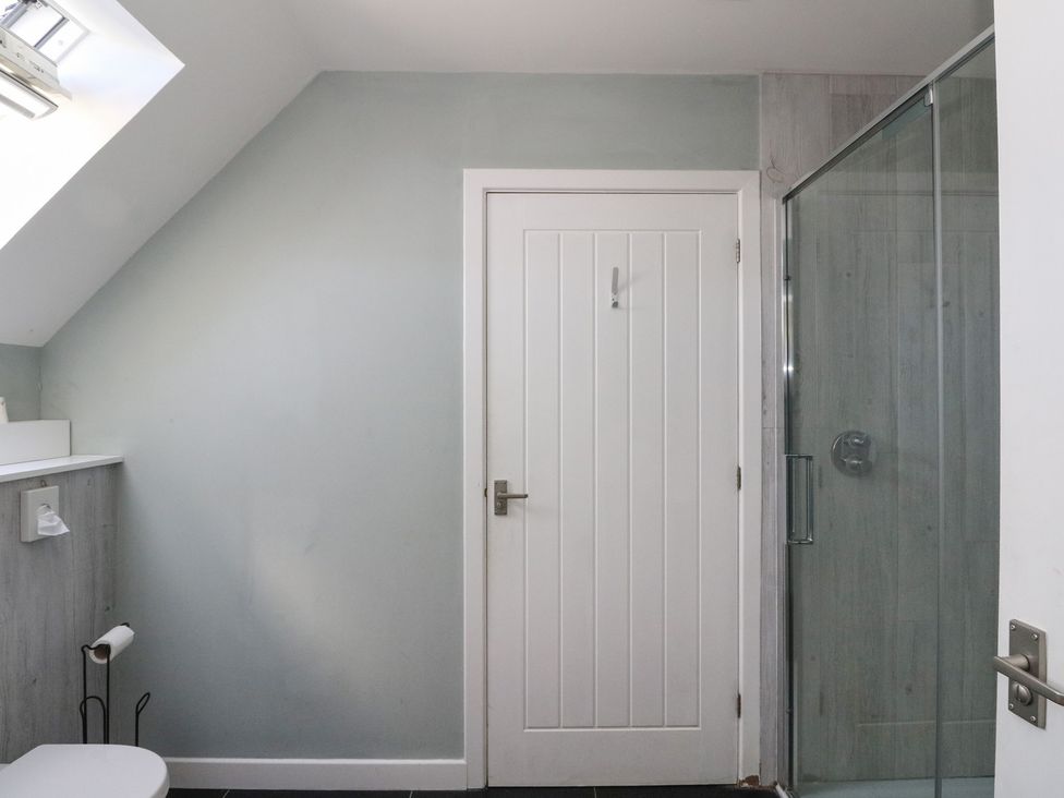 A bathroom with a white door a glass shower enclosure and a toilet paper holder at Sobrachan in Kilmartin