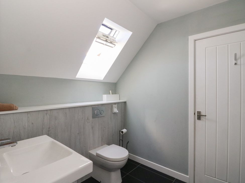 A bathroom with a wall-mounted toilet a white sink and a skylight window at Sobrachan in Kilmartin