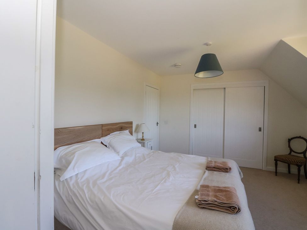 A bedroom with a double bed, bedside table with a lamp, sliding closet doors, and a chair at Sobrachan in Kilmartin