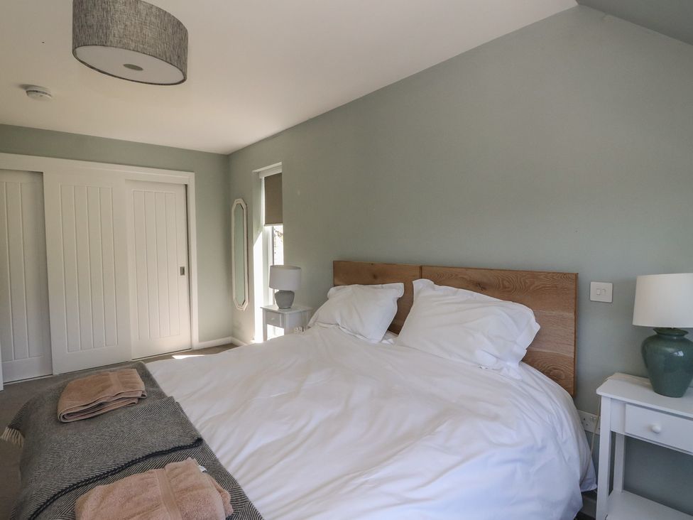 A bedroom with a double bed with white bedding bedside tables with lamps and a large mirror on the wall at Sobrachan in Kilmartin