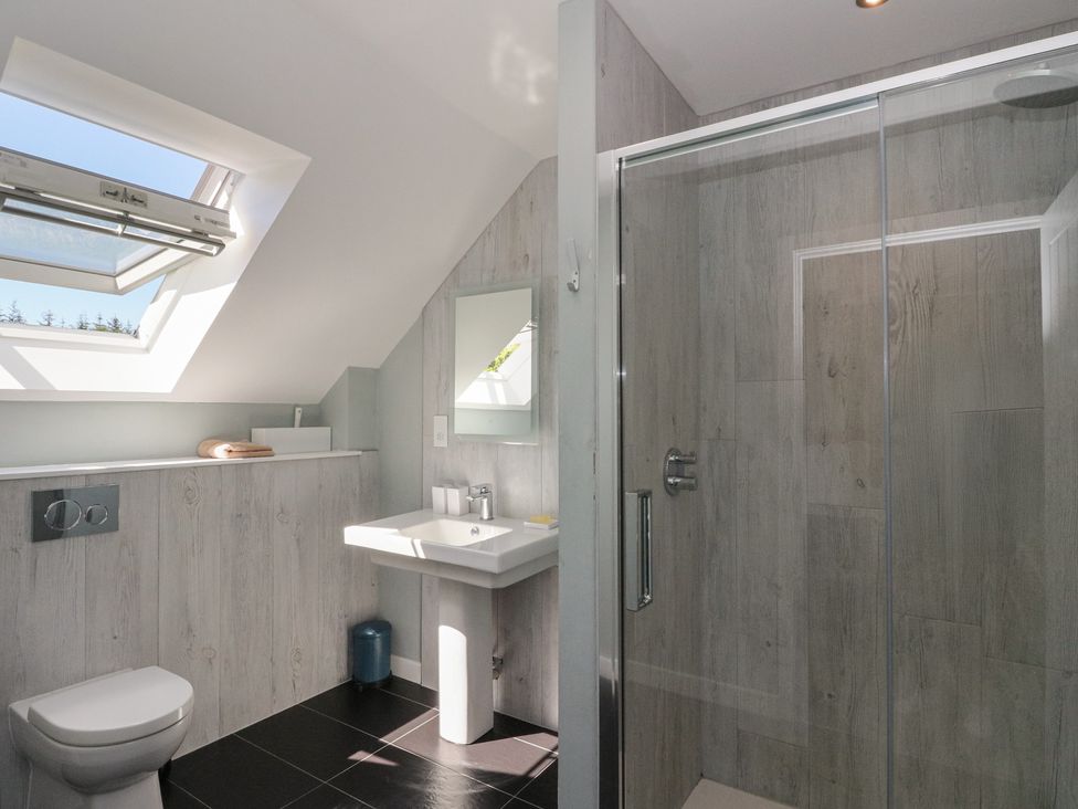 A bathroom with a toilet, pedestal sink, glass shower enclosure, and skylight window at Sobrachan in Kilmartin