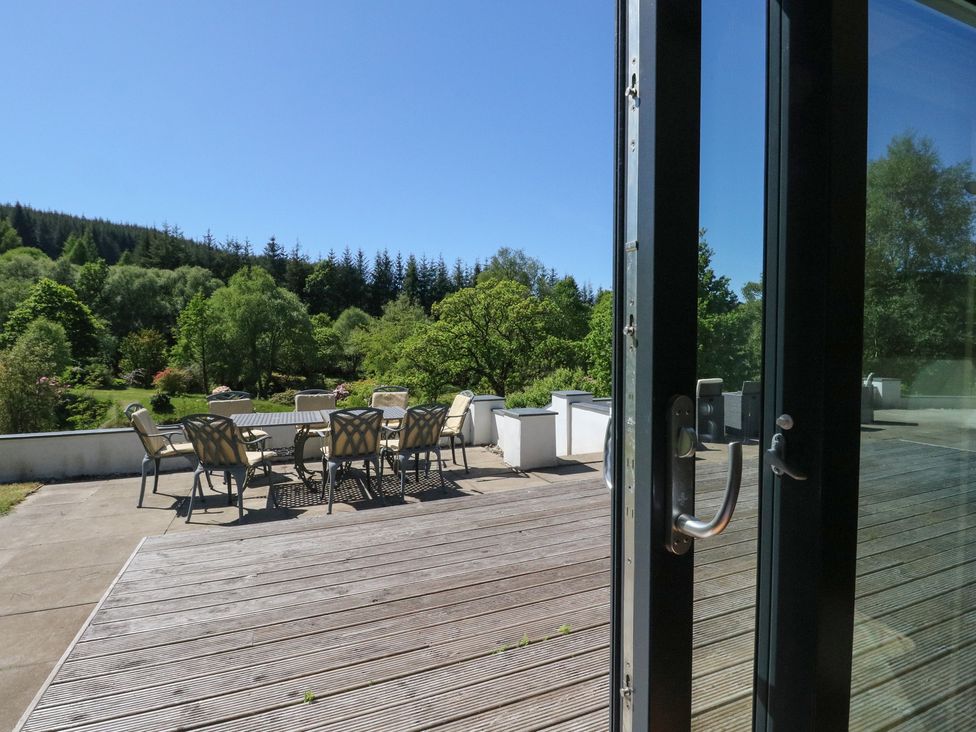 An outdoor patio with a table and chairs overlooking trees and greenery at Sobrachan in Kilmartin