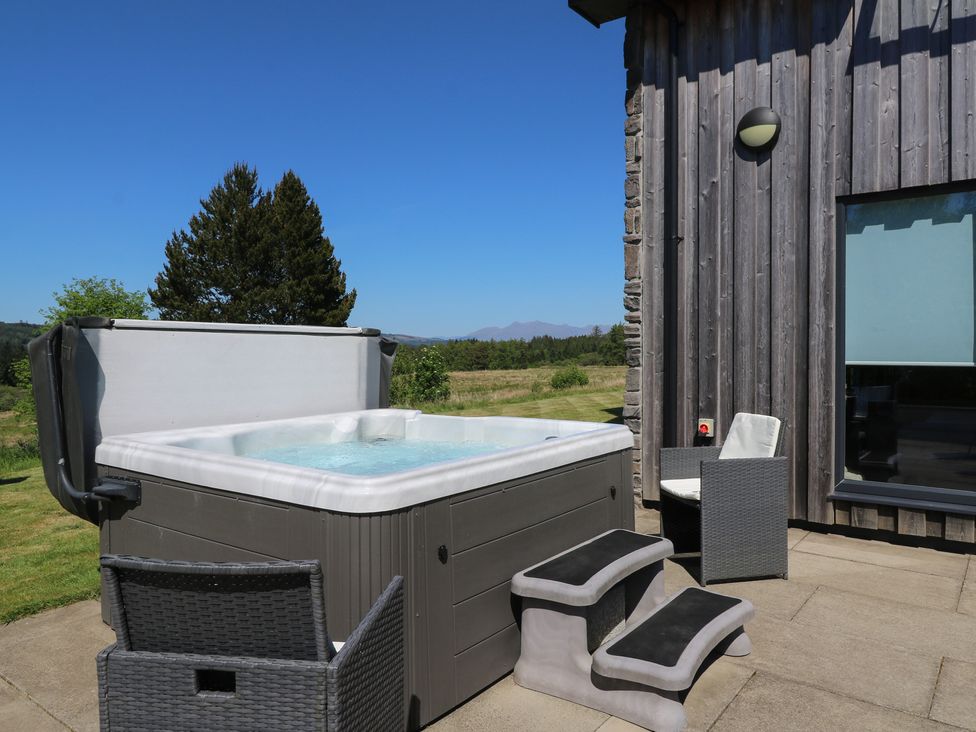 An outdoor hot tub with steps and two chairs next to a wooden building at Sobrachan in Kilmartin