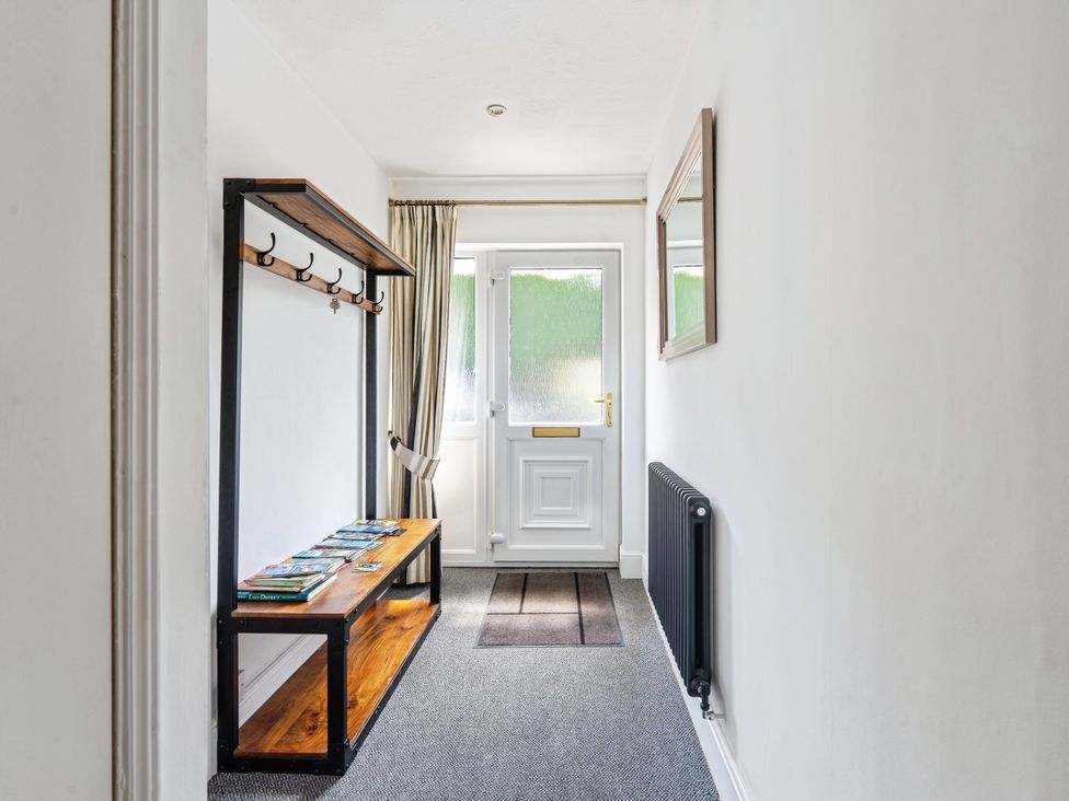 A hallway with a bench, coat hooks, and a door at Mylnebeck Lodge Bowness-on-Windermere