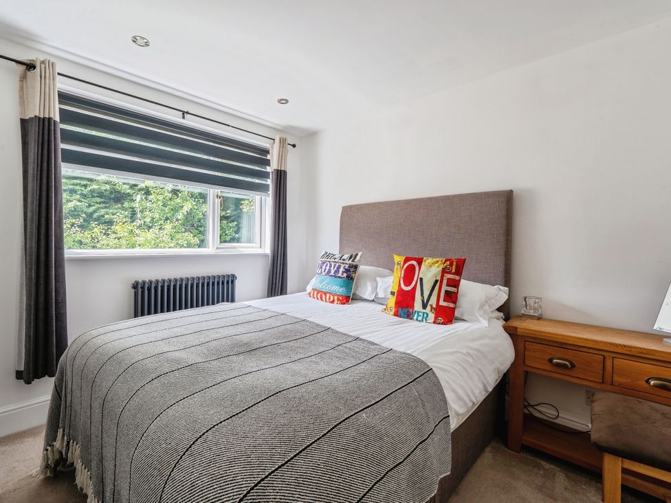 A bedroom with a bed and bedside table at Mylnebeck Lodge in Bowness-on-Windermere