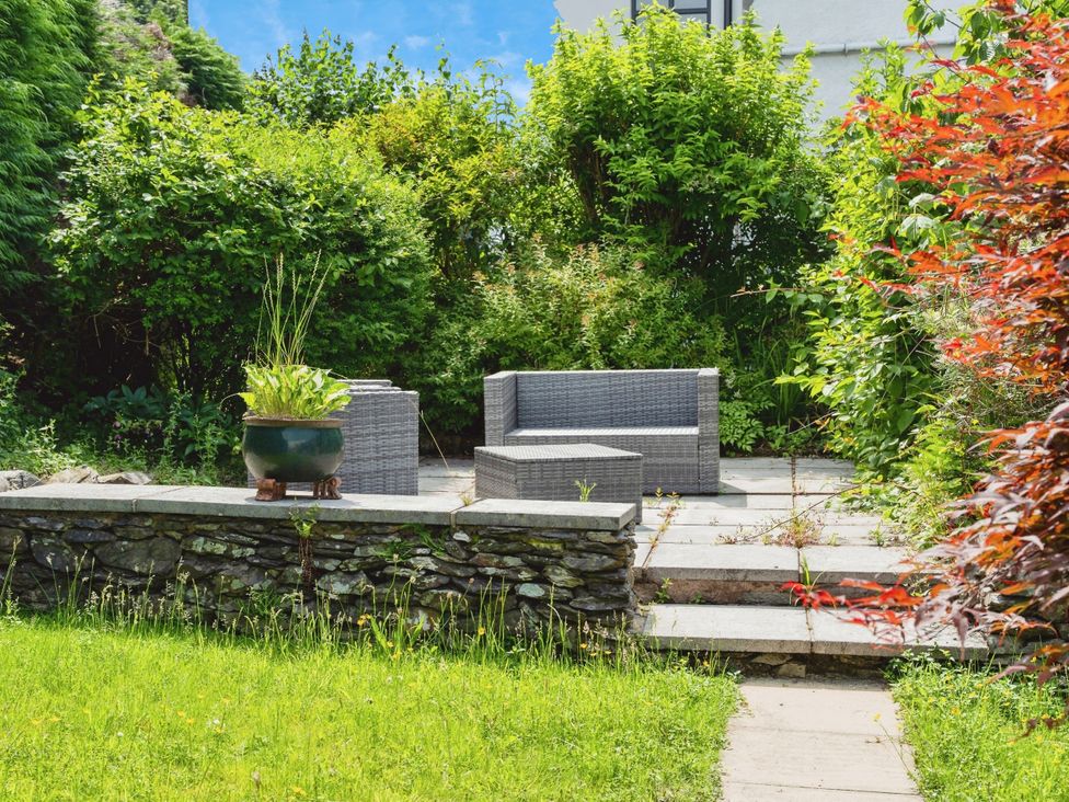 A garden with seating area and planter at Mylnebeck Lodge in Bowness-on-Windermere