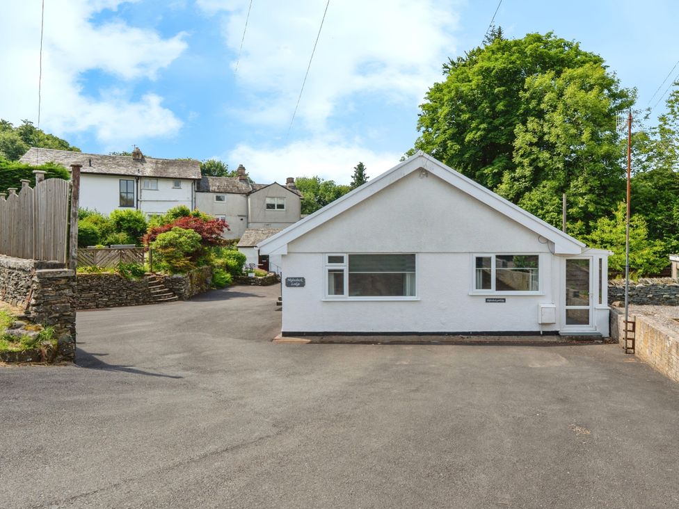 A house with a driveway and trees at Mylnebeck Lodge in Bowness-on-Windermere