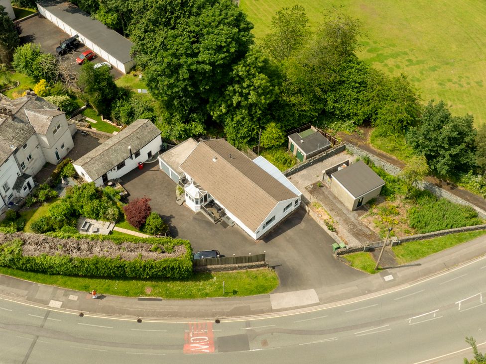 An aerial view of a house with gardens and sheds at Mylnebeck Lodge in Bowness-on-Windermere