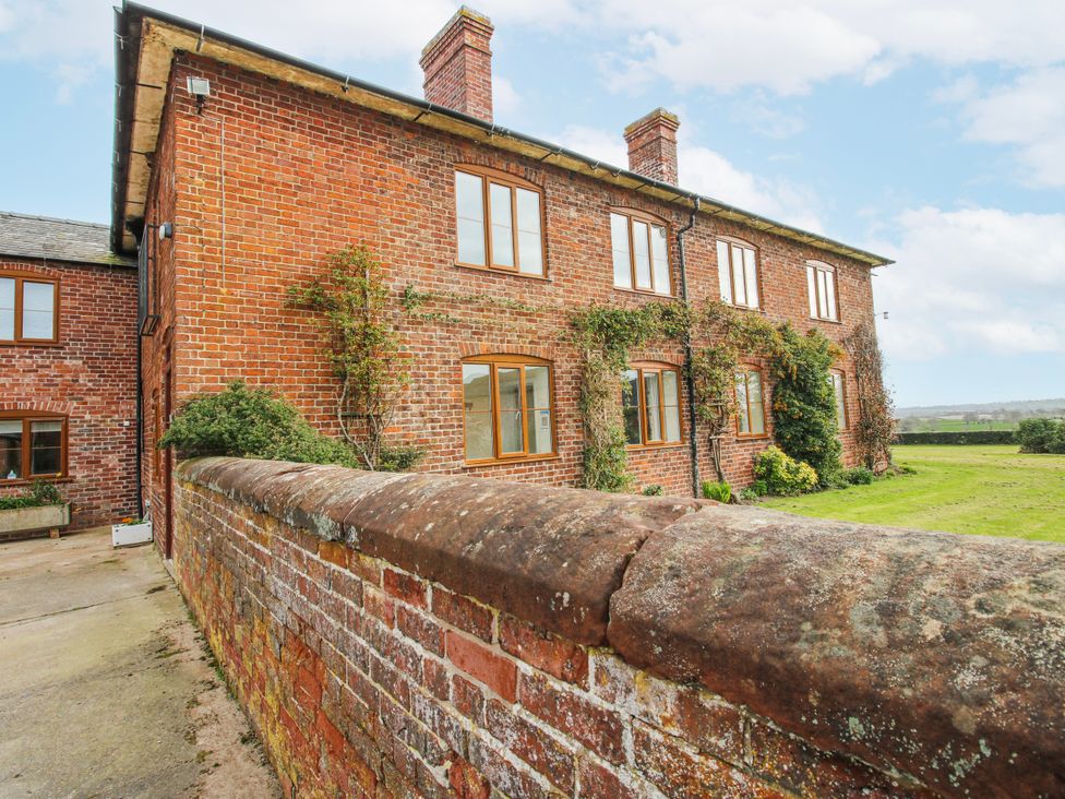 A brick house with windows and plants in an outdoor area at The Manor House at Kenwick Lodge Cockshutt near Ellesmere