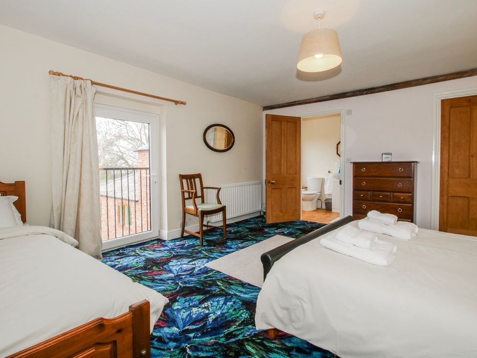 A bedroom with two beds and a balcony at The Manor House at Kenwick Lodge Cockshutt near Ellesmere