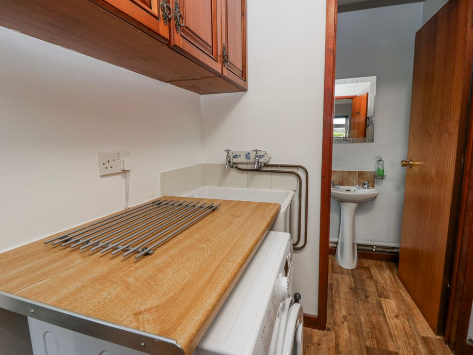 A laundry room with a washing machine and sink at Blaenywawr near Lampeter