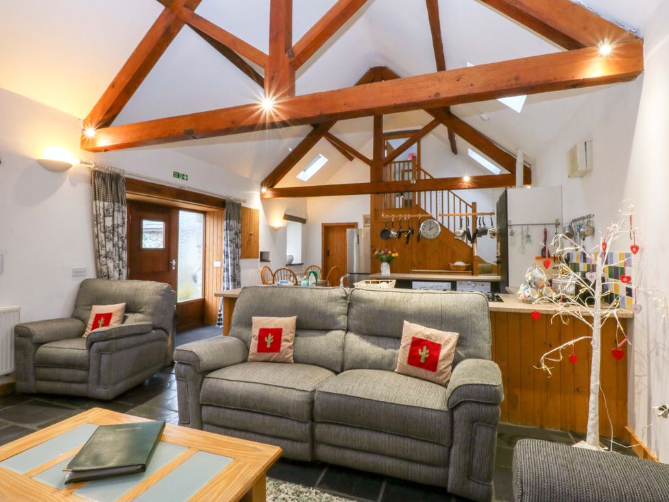A living room with a sofa, armchairs, and a dining area at Beudy Mawr Y Felinheli