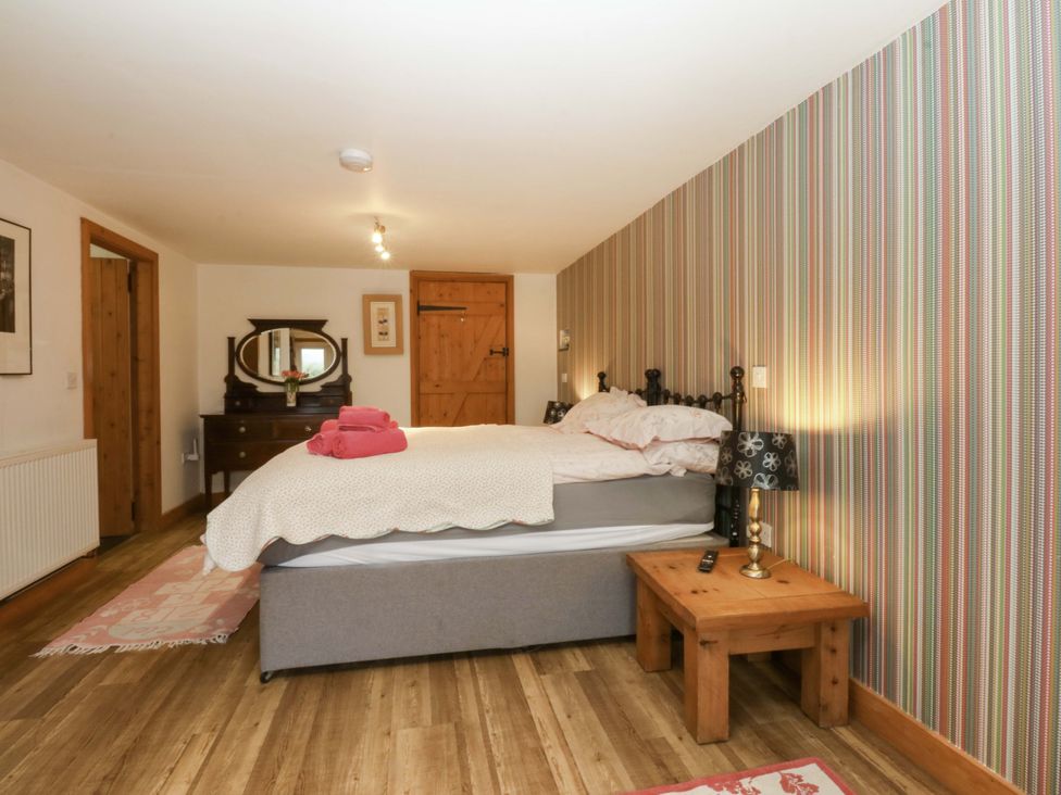 A bedroom with a bed and a mirror at Beudy Mawr Y Felinheli