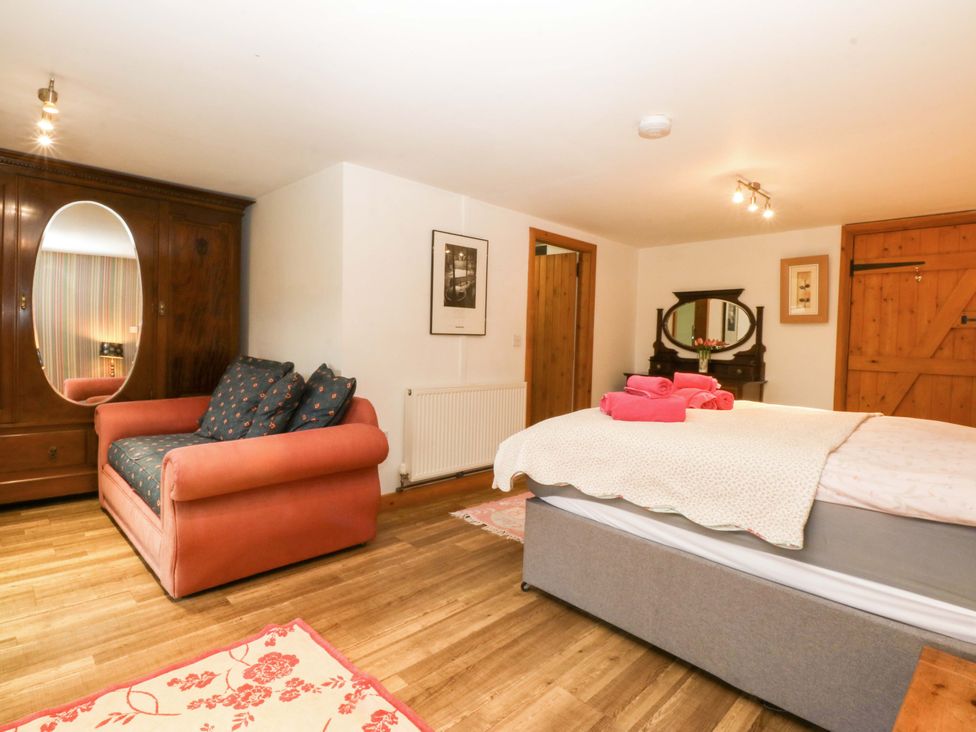 A bedroom with a bed and sofa at Beudy Mawr Y Felinheli