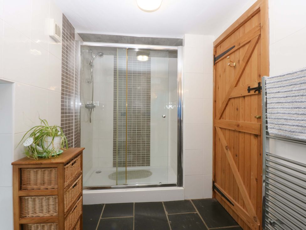 A bathroom with a shower and storage unit at Beudy Mawr Y Felinheli