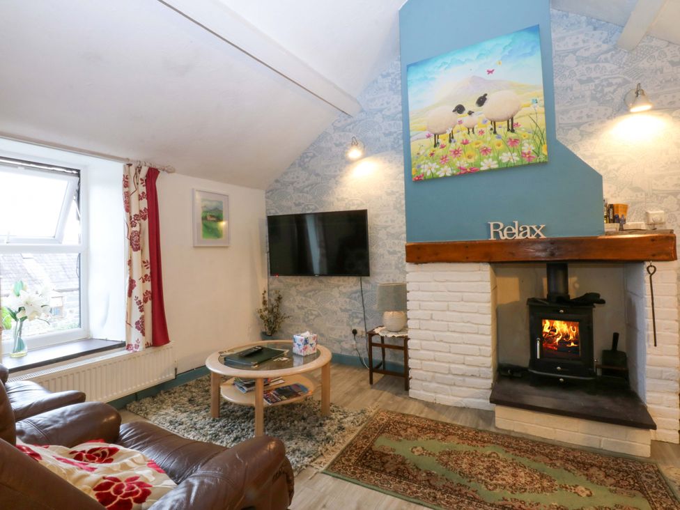A living room with a sofa, fireplace, and television at Hafod in Y Felinheli