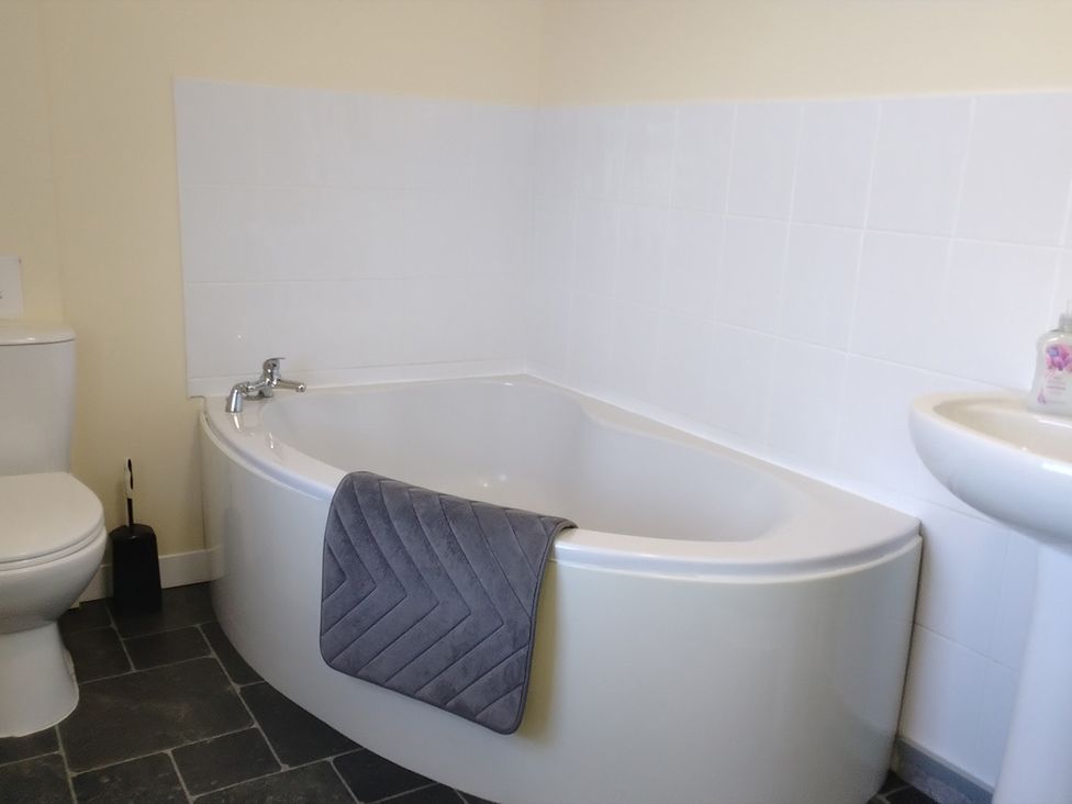 A bathroom with a bathtub, toilet, and sink at The Farmhouse in Brynsiencyn near Newborough