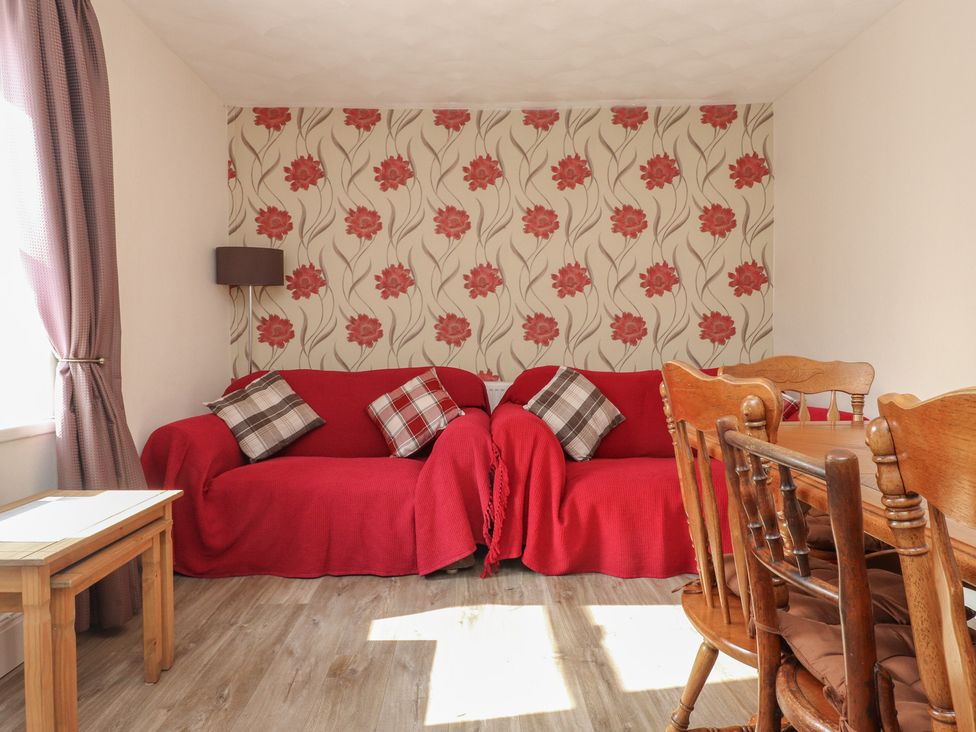 A living room with a sofa and dining table at The Farmhouse in Brynsiencyn near Newborough