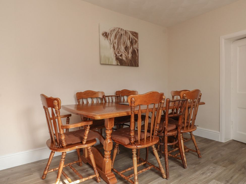 A dining room with a wooden table and chairs at The Farmhouse in Brynsiencyn near Newborough