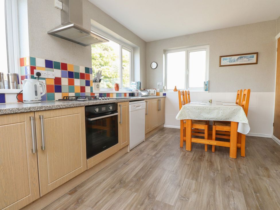 A kitchen with appliances and a table at The Farmhouse in Brynsiencyn near Newborough