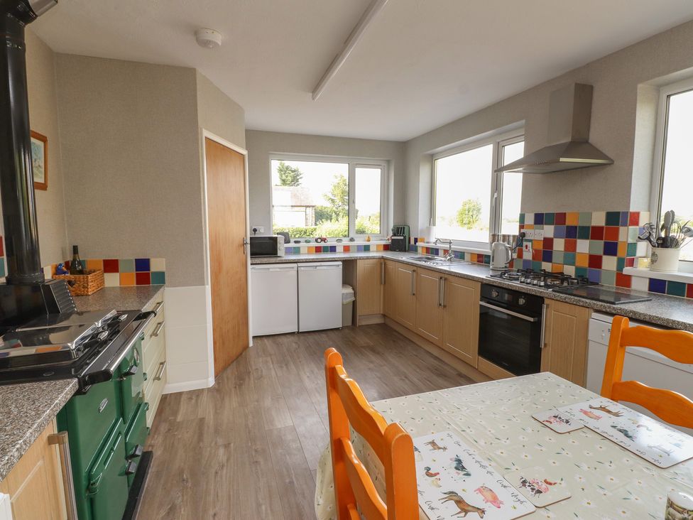 A kitchen with an oven and dining table at The Farmhouse in Brynsiencyn near Newborough