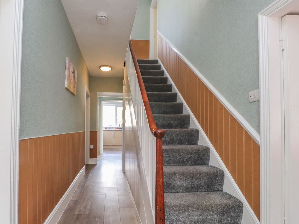 A hallway with stairs and a light fixture at The Farmhouse in Brynsiencyn near Newborough