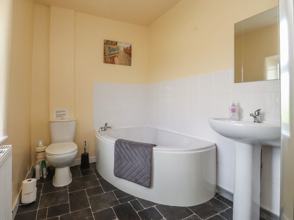 A bathroom with a bathtub, toilet, and sink at The Farmhouse in Brynsiencyn near Newborough