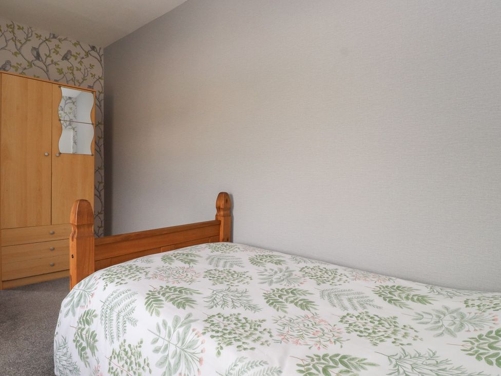 A bedroom with a bed and wardrobe at The Farmhouse in Brynsiencyn near Newborough
