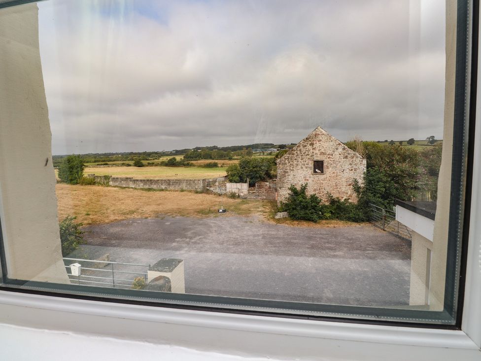 A view of a field and barn from a window at The Farmhouse in Brynsiencyn near Newborough
