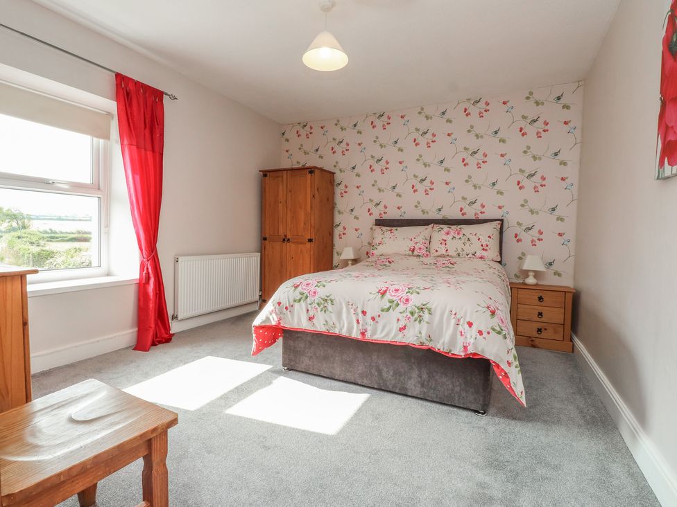 A bedroom with a bed and wardrobe at The Farmhouse in Brynsiencyn near Newborough