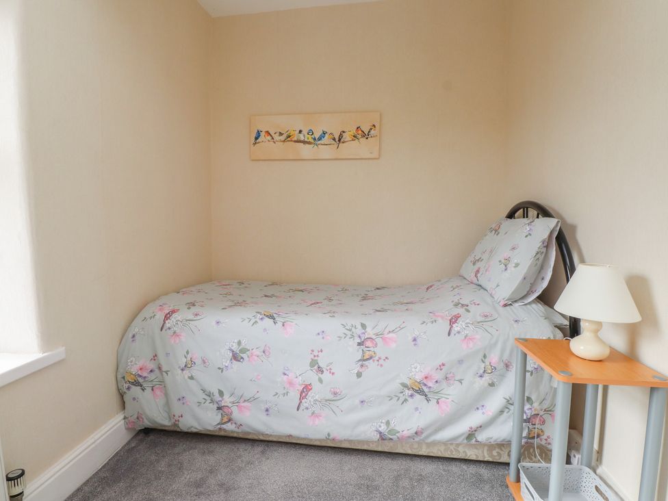 A bedroom with a single bed and bedside table at The Farmhouse in Brynsiencyn near Newborough