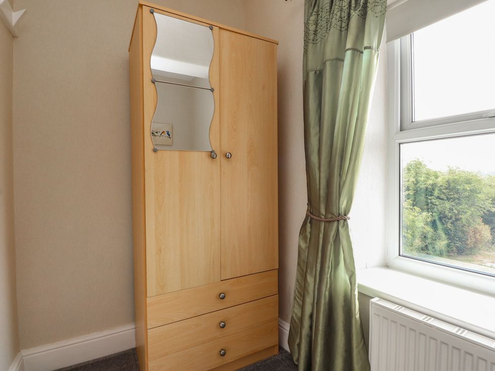A wardrobe and window with curtain in a bedroom at The Farmhouse in Brynsiencyn near Newborough