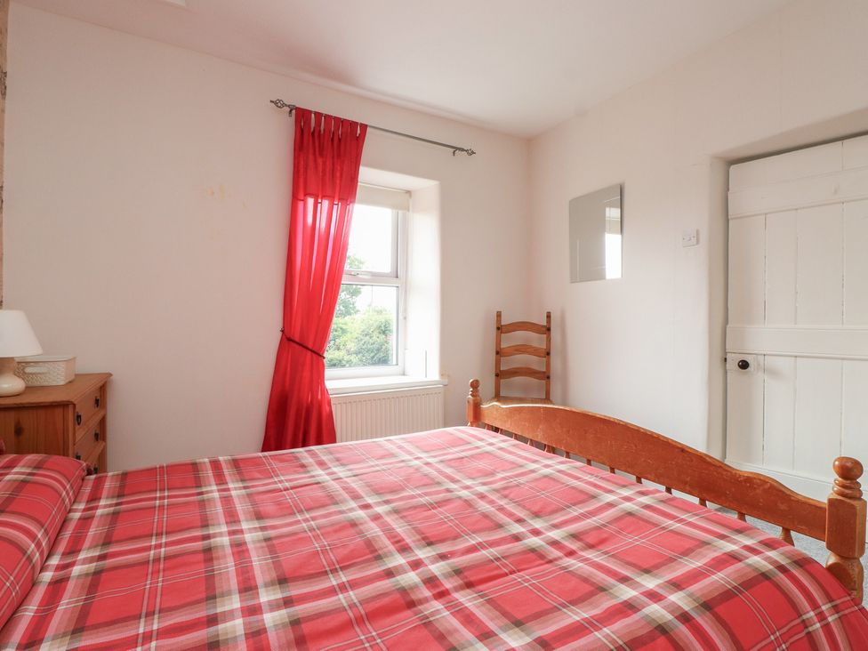 A bedroom with a bed and window at The Farmhouse in Brynsiencyn near Newborough