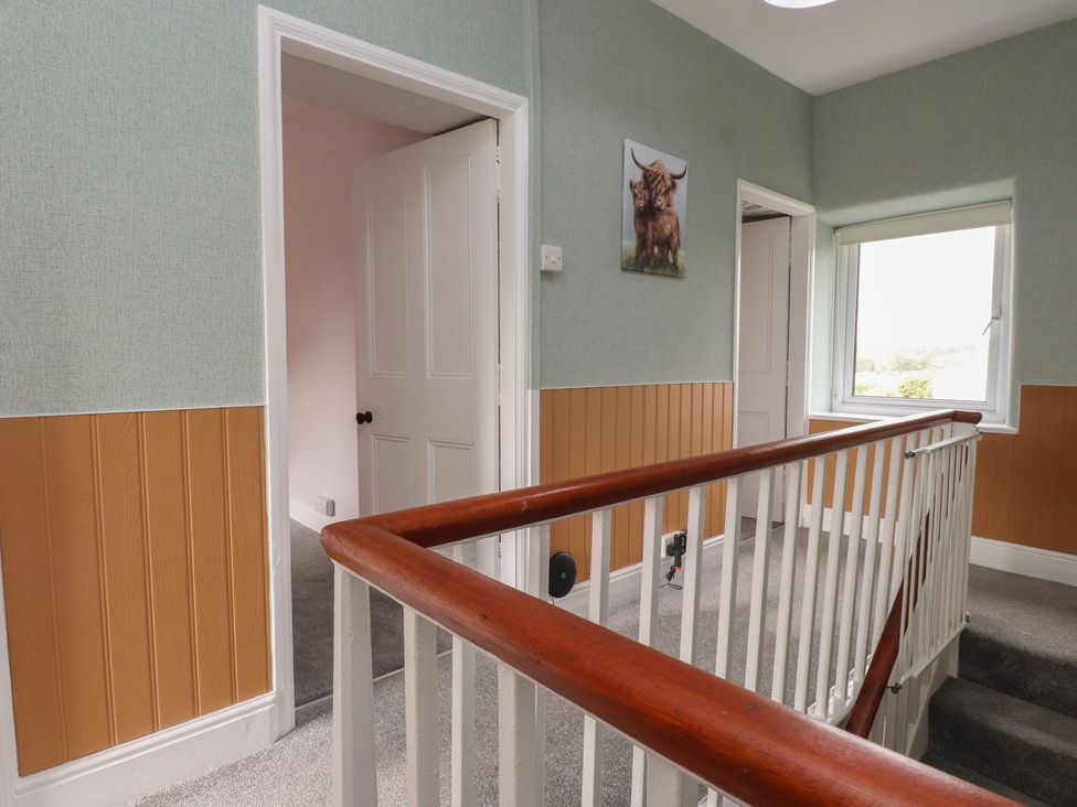 A hallway with a staircase and doors at The Farmhouse in Brynsiencyn near Newborough