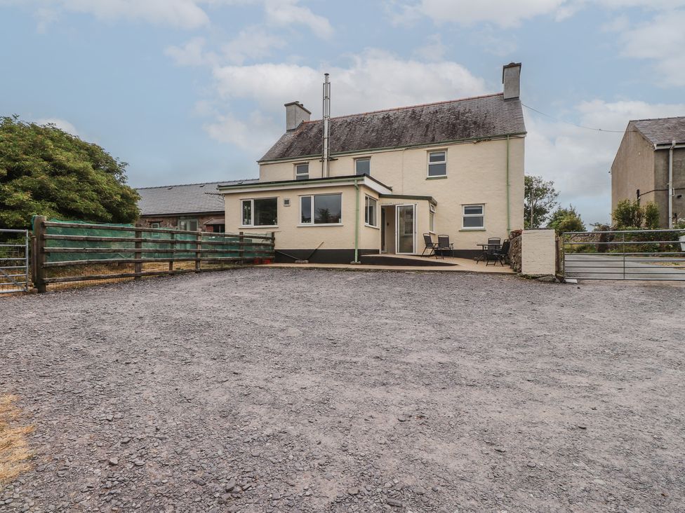 A house with a gravel area and furniture at The Farmhouse in Brynsiencyn near Newborough
